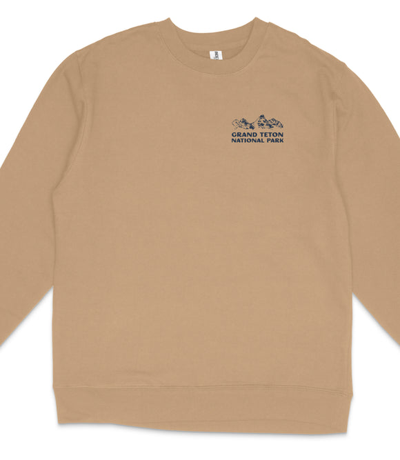 A tan long-sleeved shirt with a small embroidered logo on the left side that says "GRAND Teton NATIONAL PARK".
