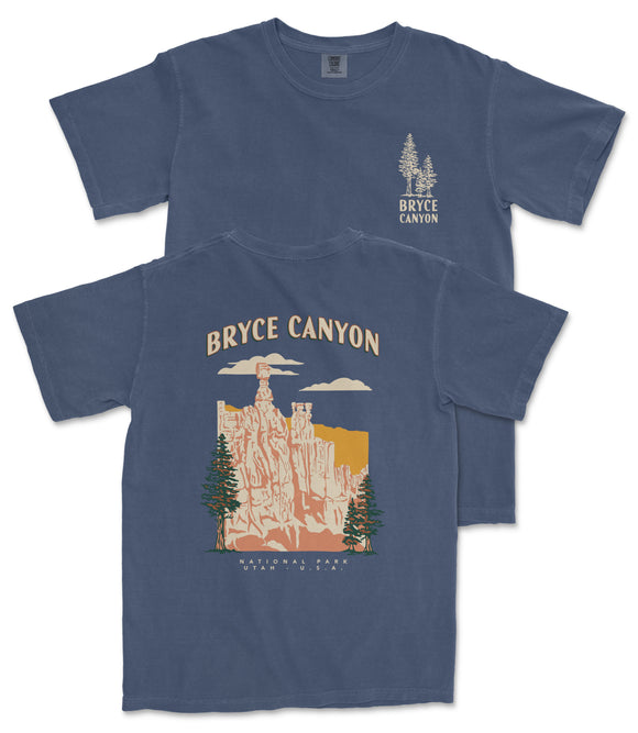 A blue t-shirt with a graphic design depicting Bryce Canyon National Park, featuring a mountain landscape with a prominent rock formation and trees.