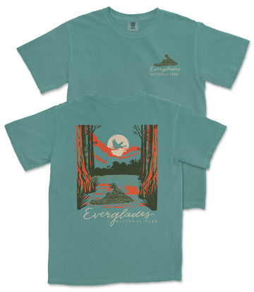 A teal-colored t-shirt with a graphic design depicting a sunset over a lake, surrounded by trees and wildlife.