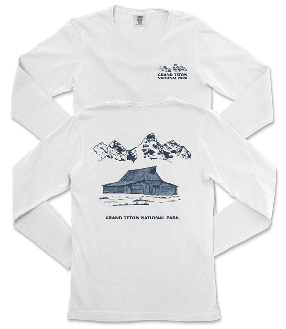 A white long-sleeved t-shirt with a graphic design depicting a cabin and mountains, along with text that reads "Grand Teton National Park".