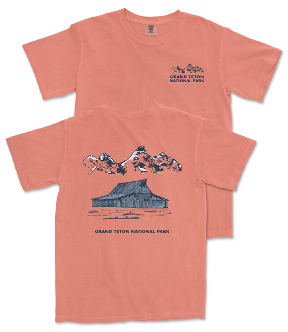 A red t-shirt with a graphic design depicting a cabin and mountains, along with the text "Grand Teton National Park".