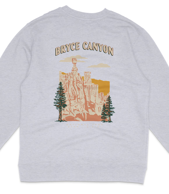 A gray sweatshirt with a graphic design depicting a scenic landscape with a tall tower, trees, and mountains.