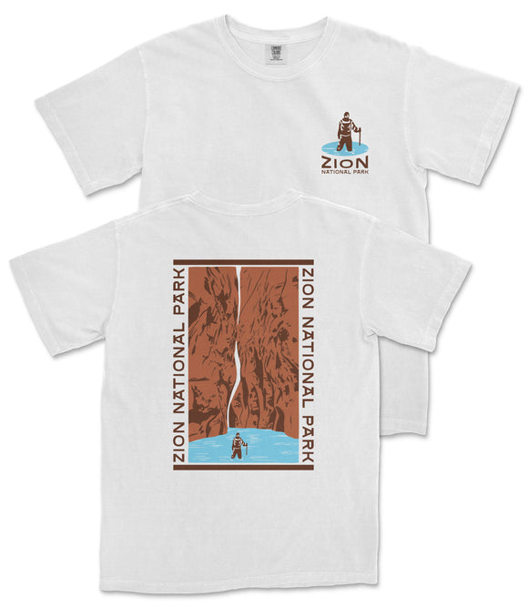 A white t-shirt with a graphic design depicting a person standing in front of a waterfall, surrounded by the text "ZION NATIONAL PARK" and a small image of a person.