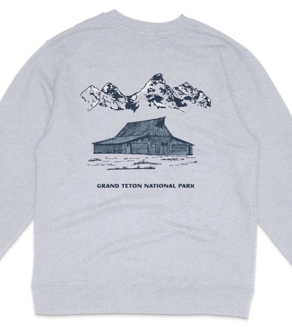A gray sweatshirt with a graphic design depicting a cabin and mountains in the background, along with the text "GRAND Teton NATIONAL PARK".