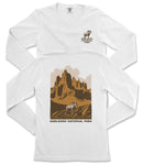 a white long-sleeved t-shirt with a graphic design depicting a mountain landscape and a goat. The text "BADLANDS NATIONAL PARK" is printed below the mountain and goat illustration.