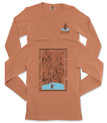 a long-sleeved orange t-shirt with a graphic design on the back, depicting a person standing in front of a waterfall.
