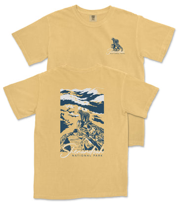 a yellow t-shirt with a graphic design depicting a person riding a bicycle on a trail in a mountainous landscape.