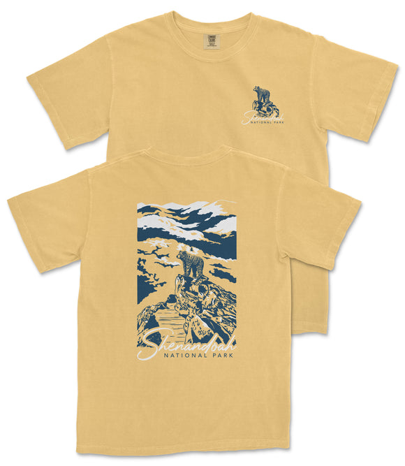 a yellow t-shirt with a graphic design depicting a person riding a bicycle on a trail in a mountainous landscape.