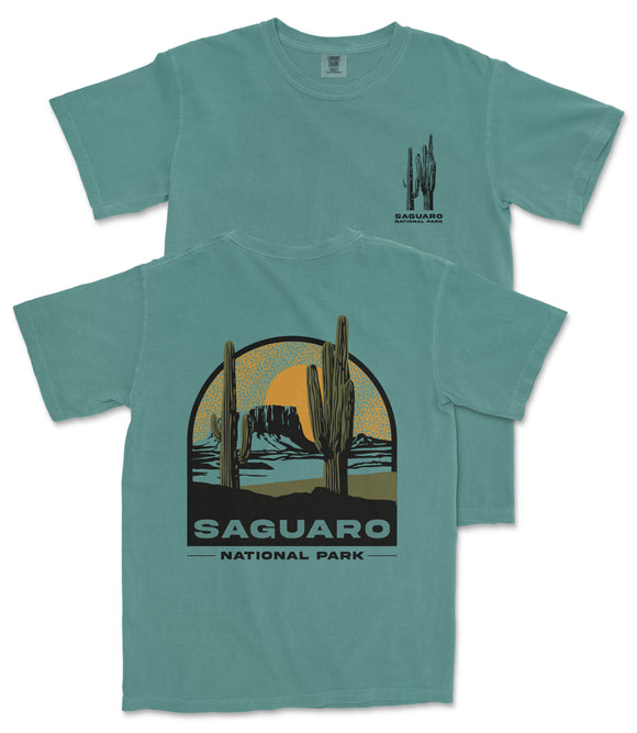 A turquoise t-shirt with a graphic design depicting a desert landscape with cacti and mountains, along with the text "Saguaro National Park".