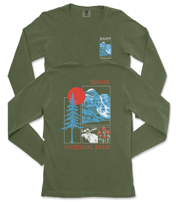 a green long-sleeved t-shirt with a graphic design featuring a mountain range, a tree, and a red sun. The text on the t-shirt reads "BANFF NATIONAL PARK".