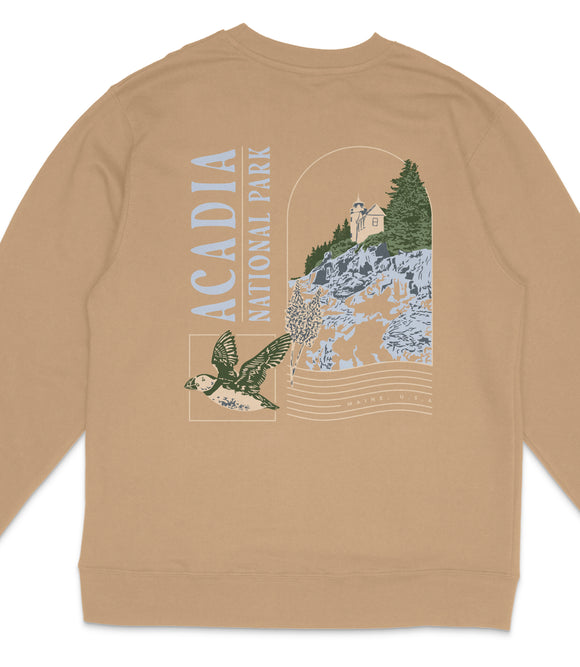 a beige sweater with a graphic design depicting a bird in flight, a castle, and a mountain landscape.