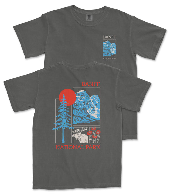 a gray t-shirt with a graphic design depicting a mountain landscape, including a sun, pine trees, and wildlife. The text on the t-shirt reads "BANFF NATIONAL PARK" and "BANFF" is written in a larger font size than the rest of the text.