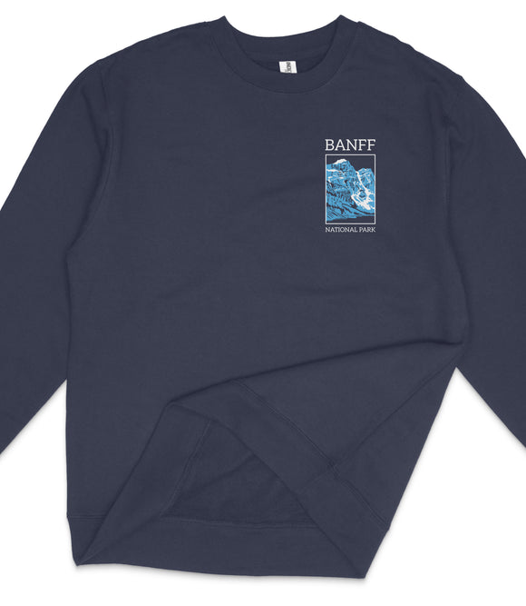 A navy blue long-sleeved shirt with a graphic design on the left side, featuring a blue and white illustration of a mountain range and the text "BANFF NATIONAL PARK".