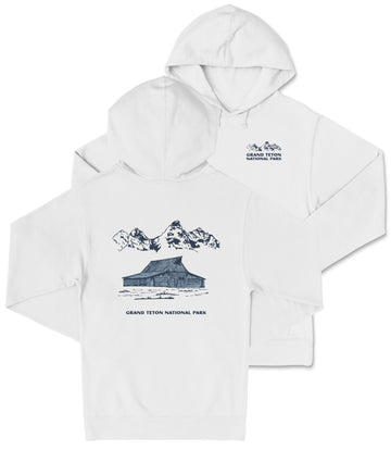 A white hooded sweatshirt with a graphic design depicting a cabin and mountains, along with text that reads "Grand Teton National Park".