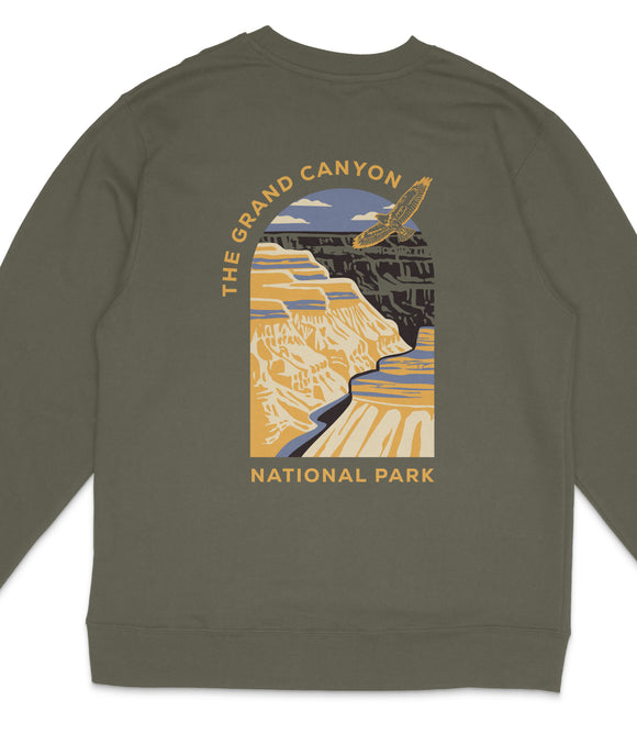 A graphic design on a grey sweatshirt depicting the Grand Canyon, with a bird flying over the canyon and the text "The Grand Canyon" and "National Park" printed on it.