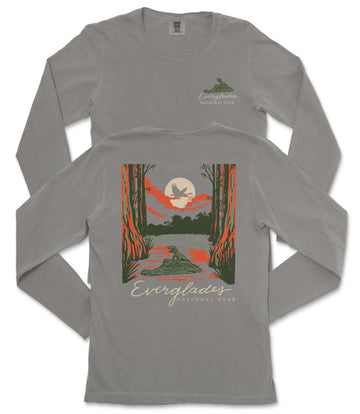 a gray long-sleeved t-shirt with a graphic design depicting a serene landscape with a lake, trees, and a bird in flight. The text on the t-shirt reads "EVERGREENES NATIONAL PARK" and "EVERGREENES".