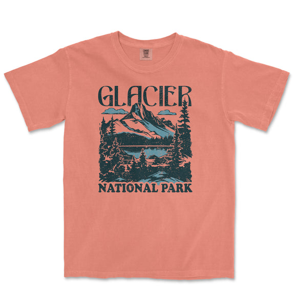 a peach t - shirt with a picture of a mountain and trees