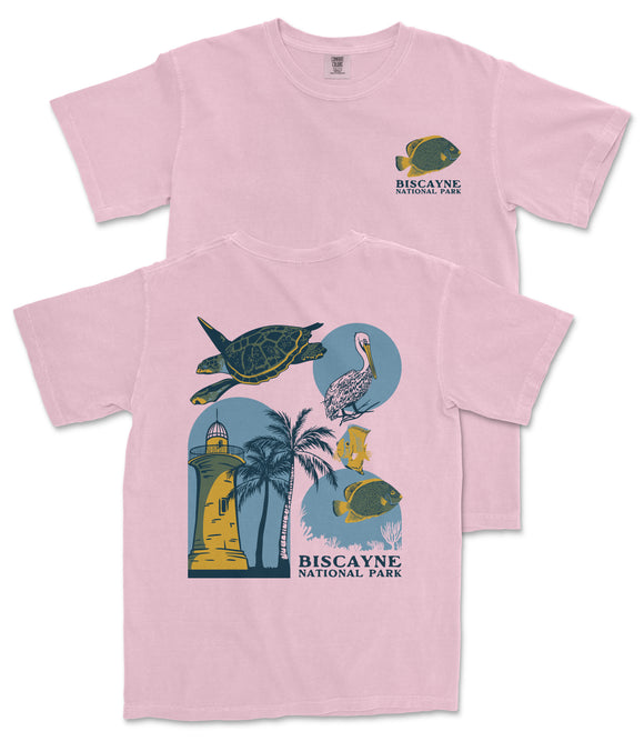 A pink t-shirt with a graphic design featuring a lighthouse, palm trees, and various marine life, including a fish and a turtle.