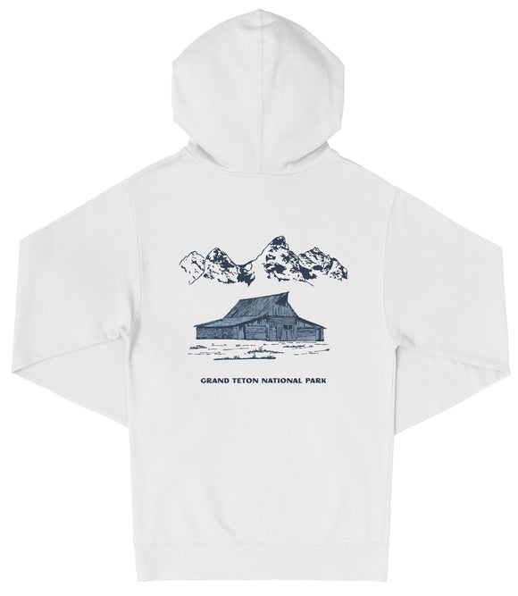 A white hooded sweatshirt with a graphic design depicting a cabin and mountains in the background, along with the text "Grand Teton National Park".