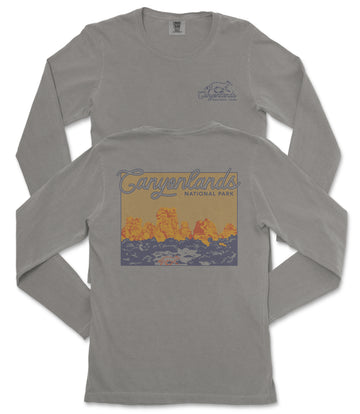 a gray long-sleeved t-shirt with a graphic design depicting a scenic landscape, including mountains and a body of water.
