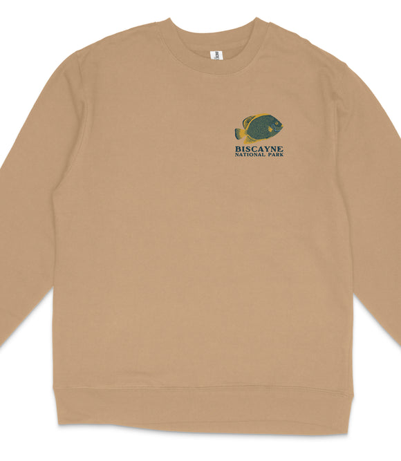 A tan long-sleeved shirt with a graphic of a fish on the left side and the text "BISCAYNE NATIONAL PARK" printed on the right side.