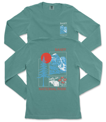 A long-sleeved green t-shirt with a graphic design featuring a red sun, blue mountains, and various other elements, along with the text "BANFF NATIONAL PARK" printed on it.