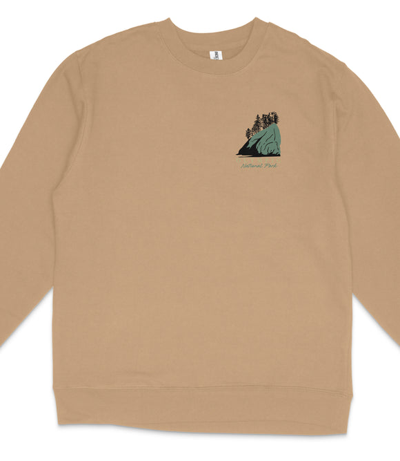 A beige long-sleeved shirt with a small graphic design on the front depicting a mountain landscape with trees.