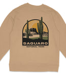a beige sweater with a graphic design depicting a desert landscape with cacti and mountains, along with the text "Saguaro National Park".