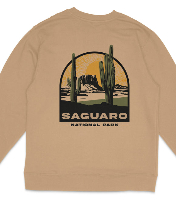 a beige sweater with a graphic design depicting a desert landscape with cacti and mountains, along with the text "Saguaro National Park".