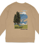 a beige sweatshirt with a graphic design depicting a scenic mountain landscape with pine trees, a mountain range, and a cloudy sky.