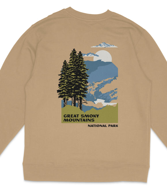 a beige sweatshirt with a graphic design depicting a scenic mountain landscape with pine trees, a mountain range, and a cloudy sky.