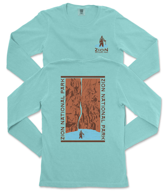 A turquoise long-sleeve t-shirt with a graphic design depicting a person standing in front of a canyon or waterfall.
