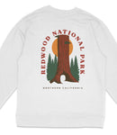 A white sweatshirt with a graphic design featuring a tall tree, a sun, and pine trees, along with the text "REDWOOD NATIONAL PARK NORTHERN CALIFORNIA".