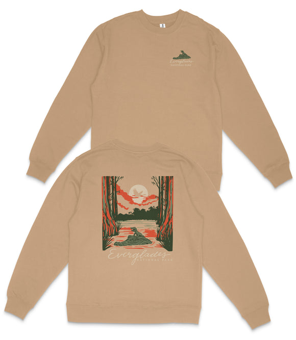 a tan sweatshirt with a graphic design on the back, depicting a sunset over a forest.