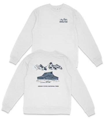 A white long-sleeved shirt with a graphic design depicting a cabin and mountains, along with the text "GRAND Teton NATIONAL PARK".