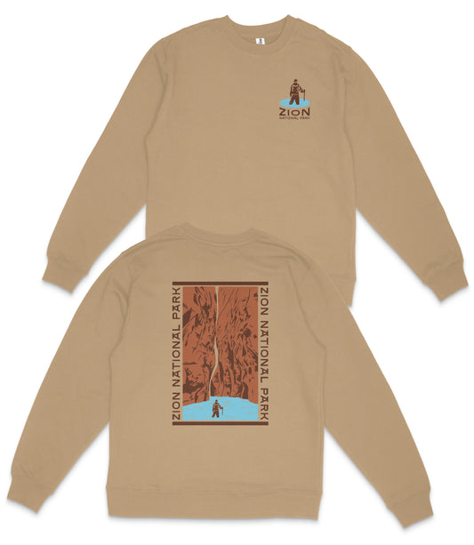 a tan sweatshirt with a graphic design on the back, depicting a mountain range with a person standing in the foreground.