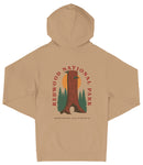 A beige hooded sweatshirt with a graphic design depicting a tall tree with a sun-like symbol in the center, surrounded by pine trees.