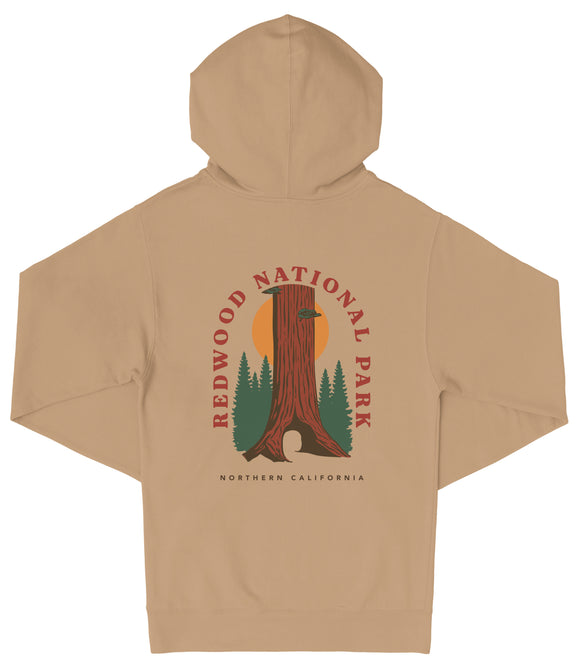 A beige hooded sweatshirt with a graphic design depicting a tall tree with a sun-like symbol in the center, surrounded by pine trees.