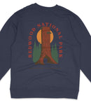 A navy blue sweatshirt with a graphic design featuring a tall tree with a sun-like symbol in the background, surrounded by pine trees and a sunset.