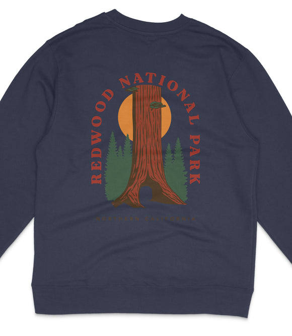 A navy blue sweatshirt with a graphic design featuring a tall tree with a sun-like symbol in the background, surrounded by pine trees and a sunset.