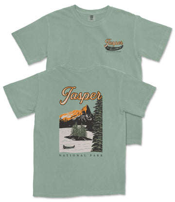 A green t-shirt with a graphic design depicting a scenic landscape with mountains, trees, and a lake, along with the text "Jasper National Park".