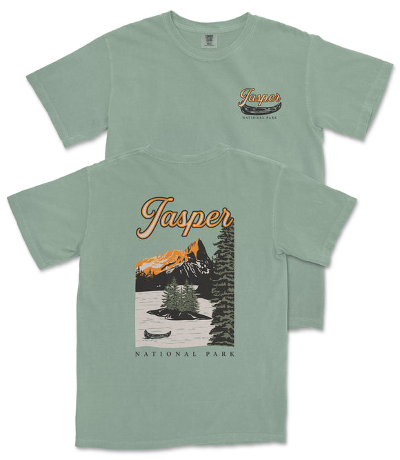 A green t-shirt with a graphic design depicting a scenic landscape with mountains, trees, and a lake, along with the text "Jasper National Park".