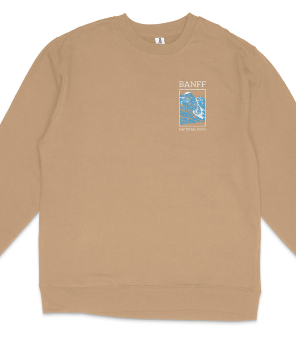 A tan long-sleeved shirt with a graphic design on the front, featuring a blue and white image of a mountain range and the text "BANFF NATIONAL PARK".